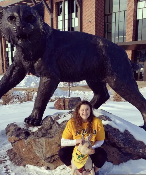 Student in front of Wildcat statue in snow