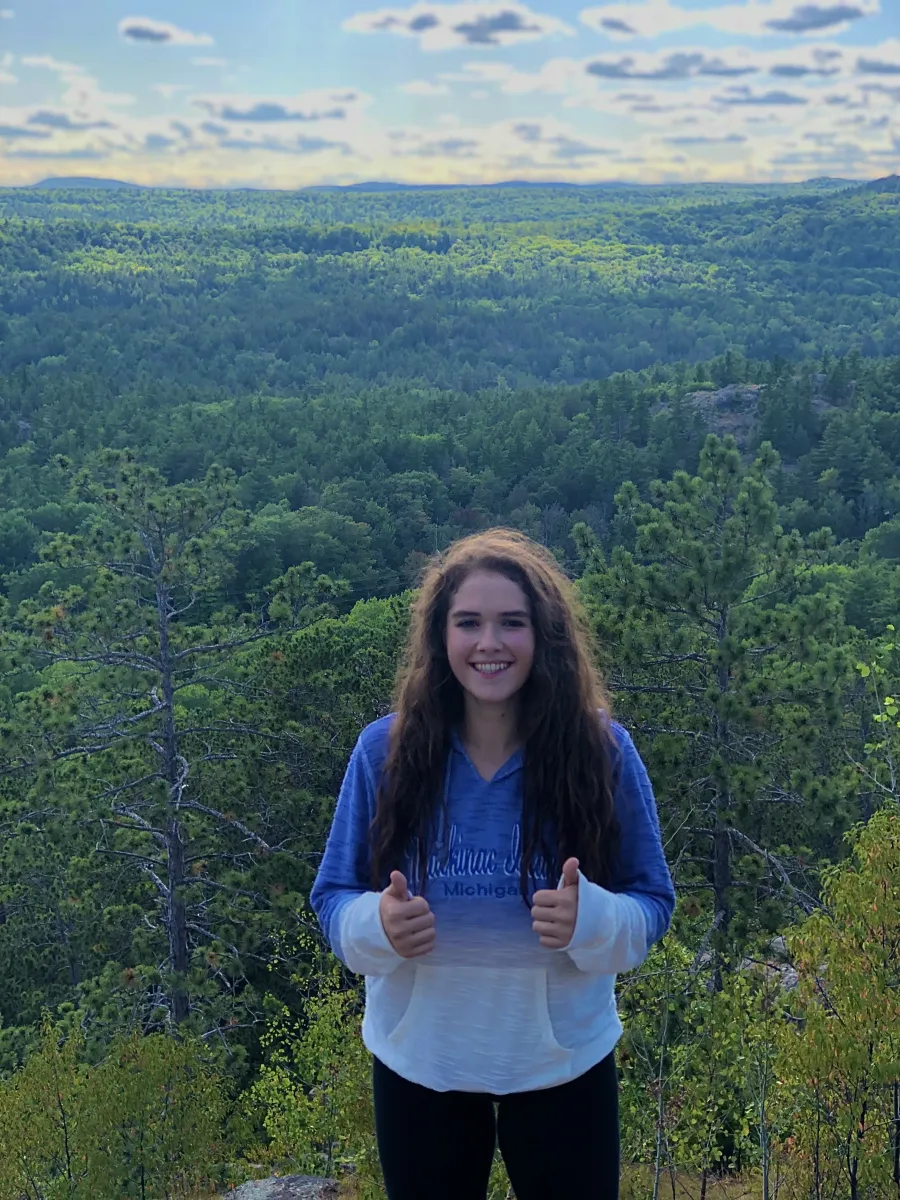 Girl giving thumbs up on top of a hill
