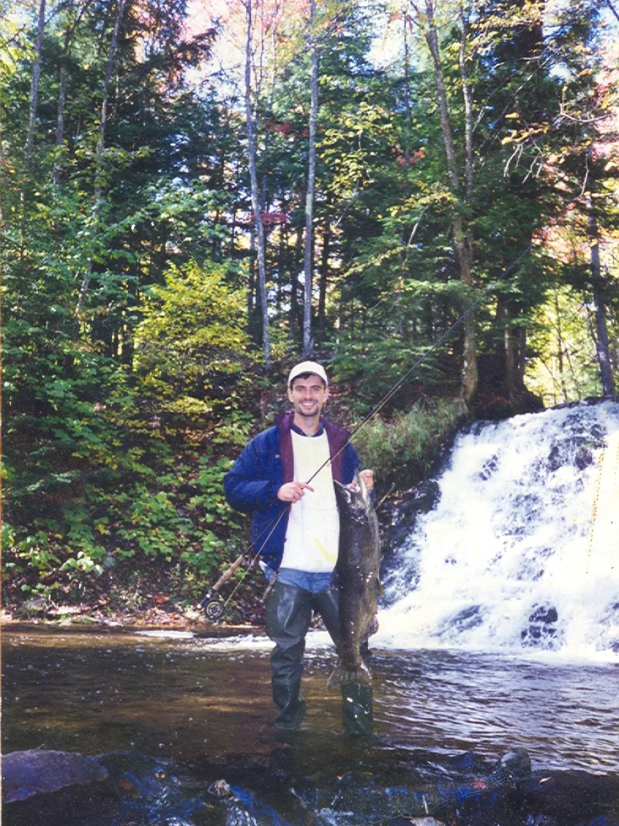 Man in front of waterfall holding fish