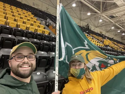 Ethan and another student with an NMU flag at a hockey game