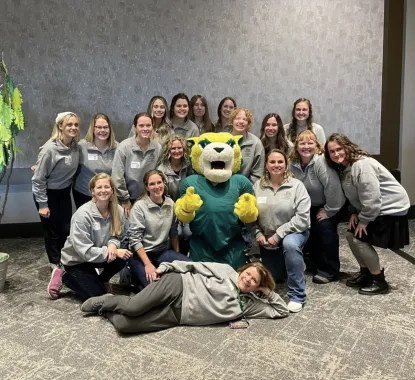 A nursing cohort poses for a photo with NMU's mascot Wildcat Willy