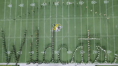 NMU's Marching Band performing during the halftime show of a football game, making a "Wildcats" formation