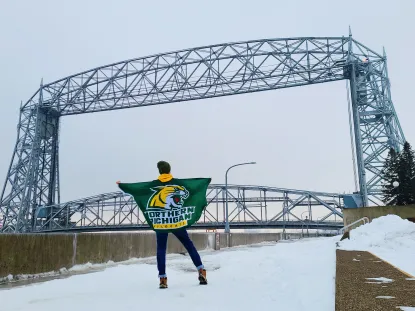 Thomas with an NMU flag in front of a bridge in Duluth, MN