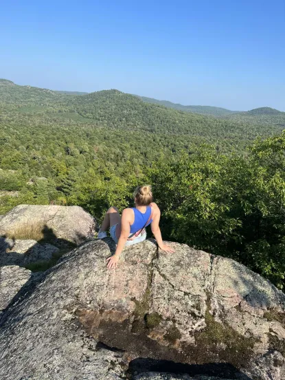 Woman sitting on a rock overlooking woods
