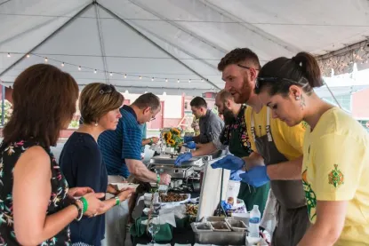 people serving food from a buffet under a tent