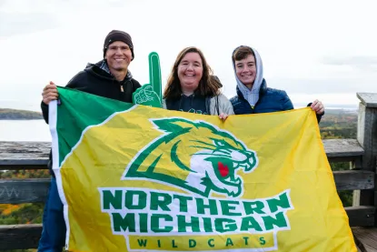 a mother, father, and son holding a NMU flag