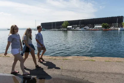 three people walking on the side walk in the Lower Harbor of Marquette