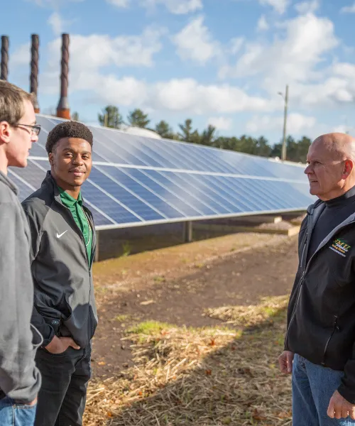 Two students and professor with solar panel array