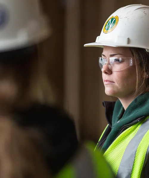 female construction student wearing a hard hat and safety glasses