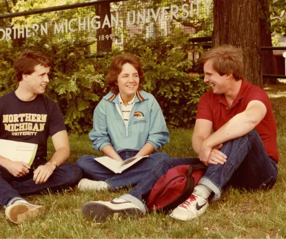 Two male students and one female relax on campus, circa 1988