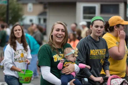 Group of female NMU alumni march in the homecoming parade with their children