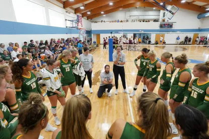 NMU Women's volleyball players and their coach huddle in the school gymnasium on Mackinac Island