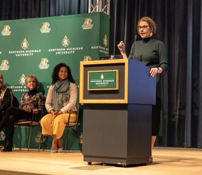 Provost stands at an Northern Michigan University branded podium addressing a crowd