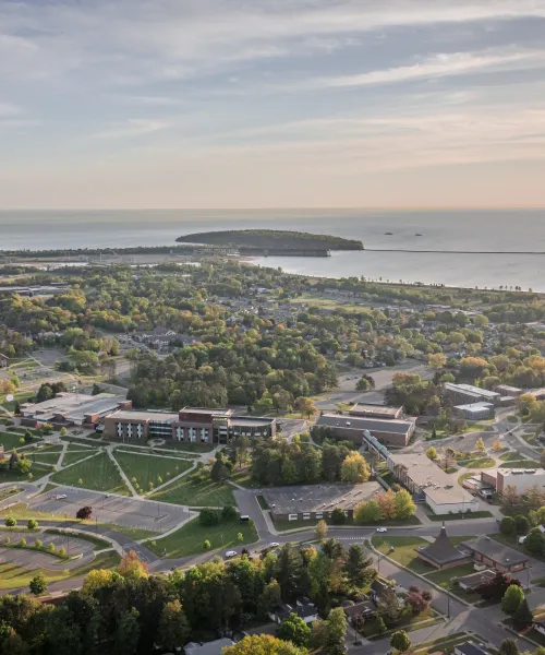 Aerial shot of NMU's campus featuring Jamrich Hall and the academic mall, the Dome, and Lake Superior