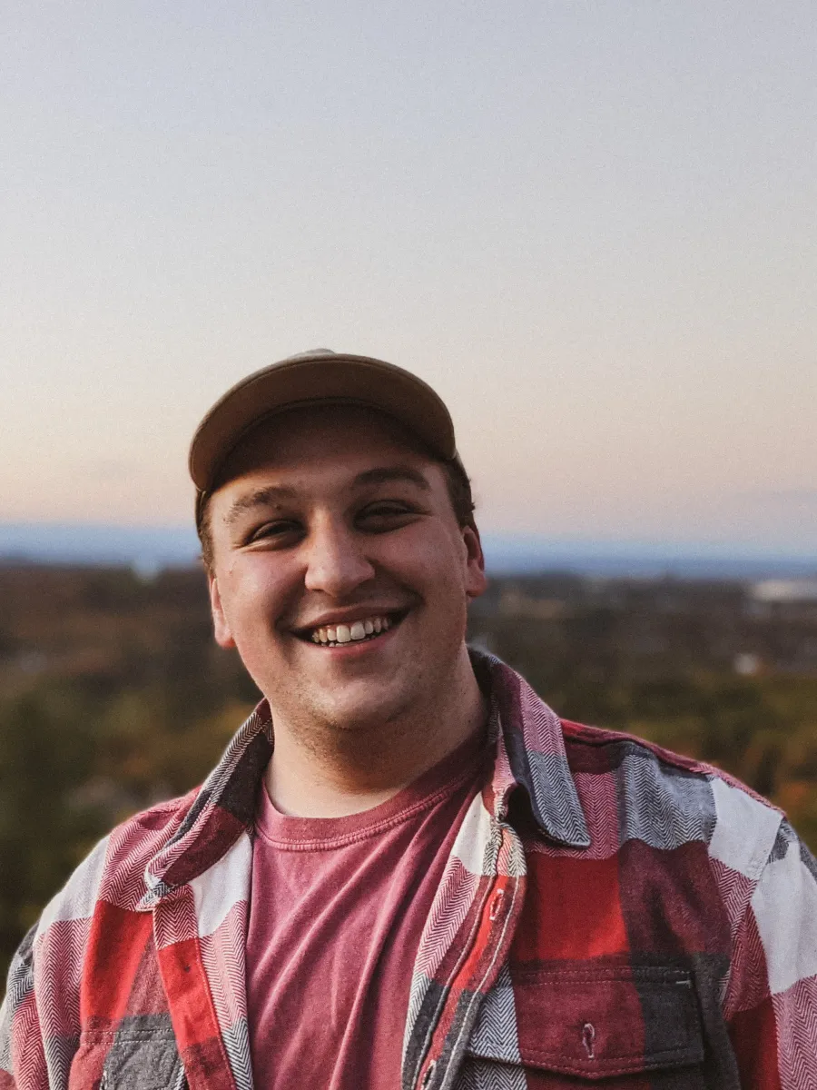 Smiling student, wearing a hat, red and white plaid shirt