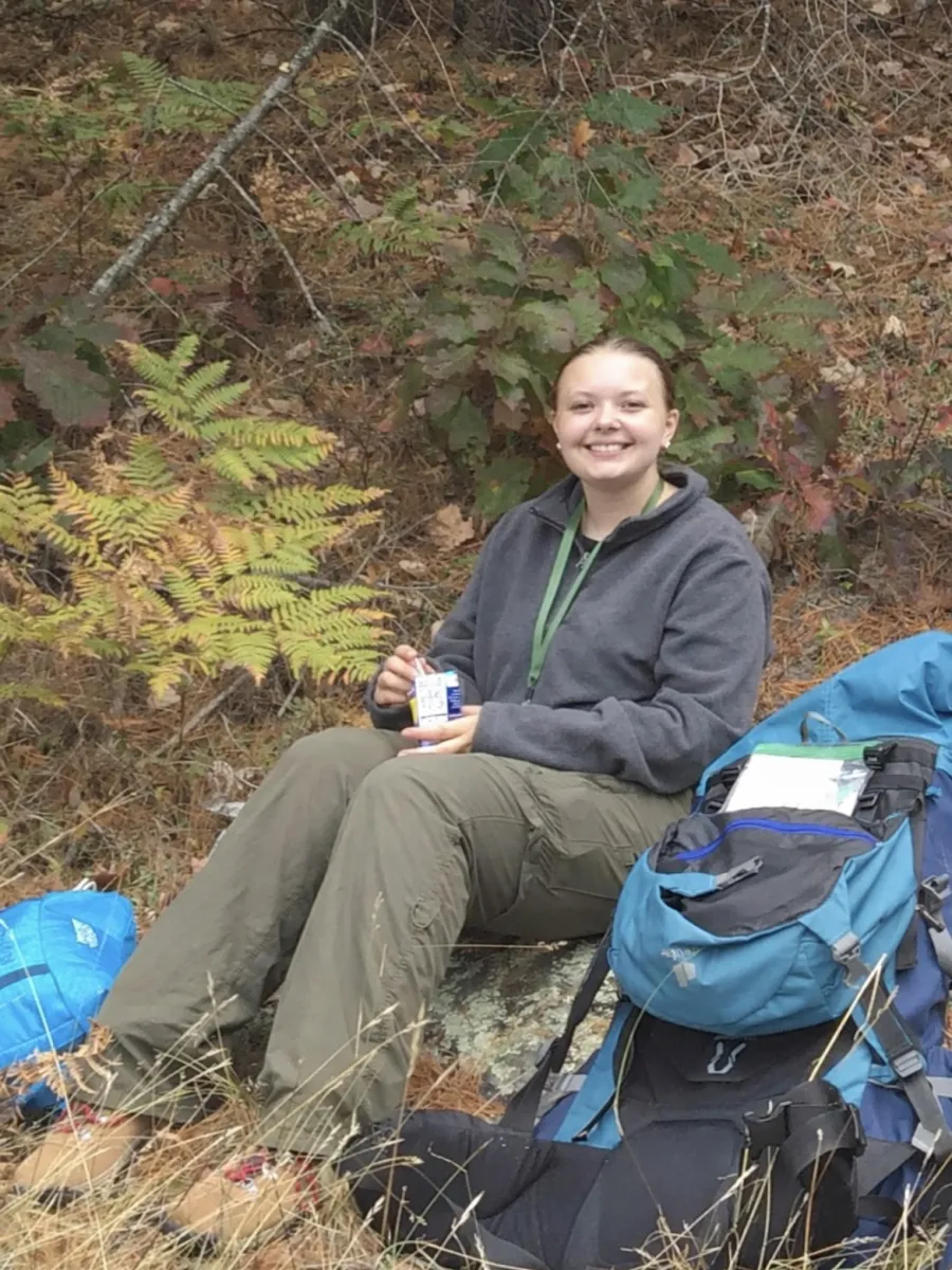 Mackenzie sitting by their pack in forest