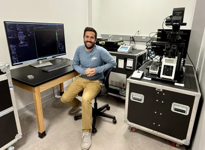 Dr. Danny Lebert poses is his lab sitting in front of his computer