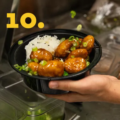 Fresh chives being sprinkled on bowl of rice and chicken