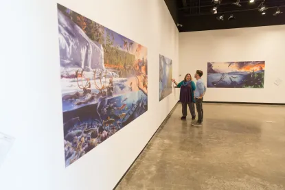 Two people look at a large format art piece in a museum