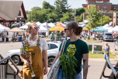 Two girls with flowers leave the Marquette Farmer's Market