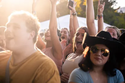 College students in cowboy hats cheer in a crowd