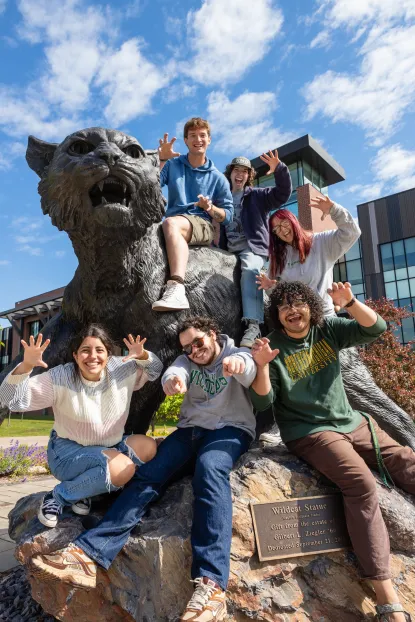 A group of NMU students posing at the Wildcat Statue