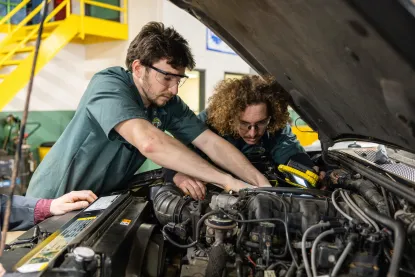 Two youths working under hood of car