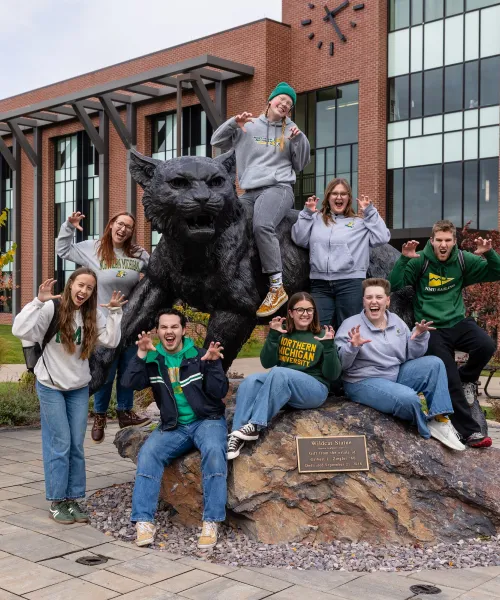 Group of students surround the NMU Wildcat Statue