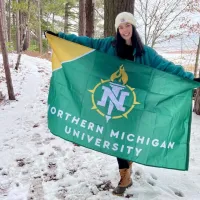 Liz Preston holding NMU flag in snowy forest