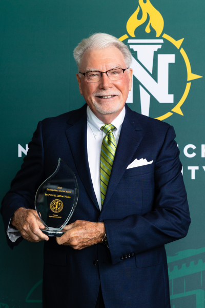 Dr. Lapine wears a navy suit as he smiles for a photo while holding his award