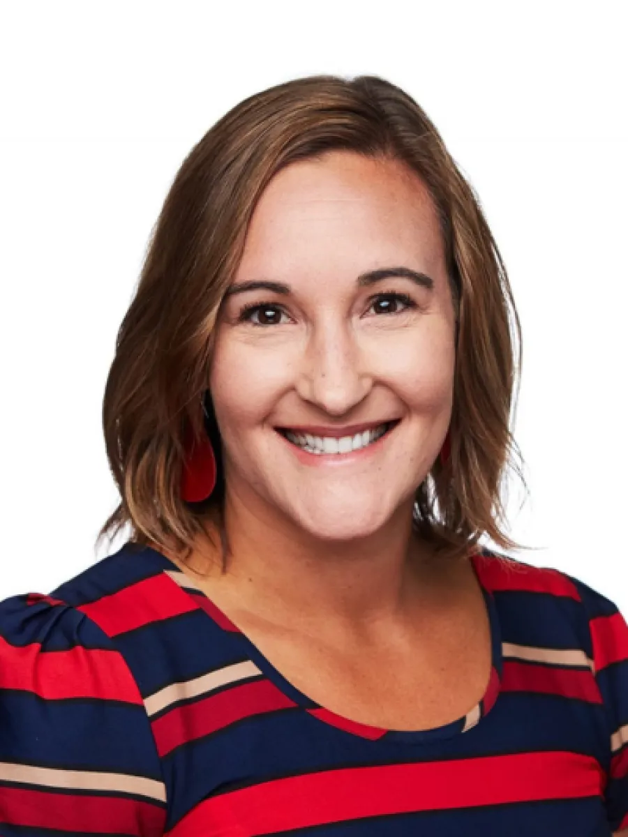 Headshot of Jenna Zdunek smiling in a striped blue and red shirt against a white background.