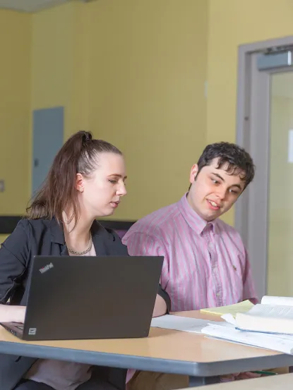 Students examining a laptop computer and book