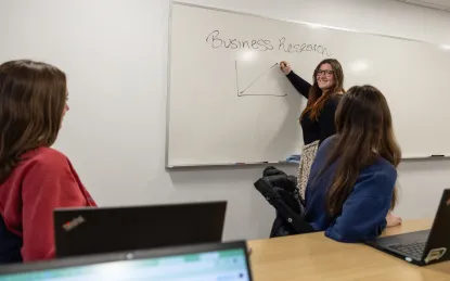 three students working at a white board in a library study room