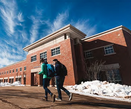Two people walking in front of Weston Hall