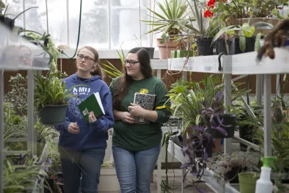 Two female students in NMU's greenhouse