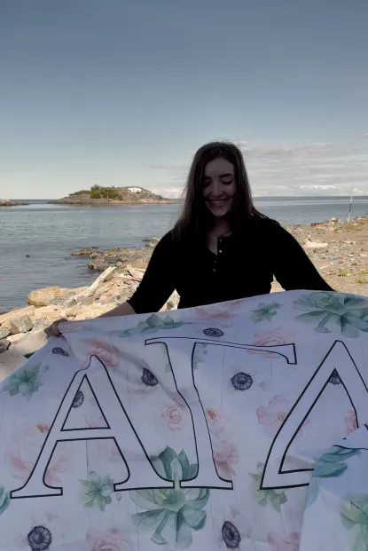 Jessica holding a flag for her sorority on the beach