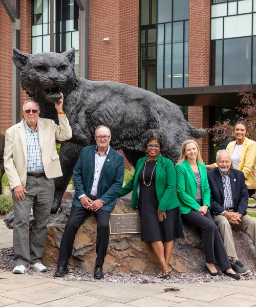 NMU Board of Trustees in front of the Wildcat Statue outside Jamrich Hall