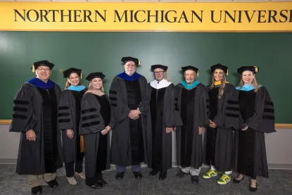 Board members standing in front of a banner that reads "Northern Michigan University"