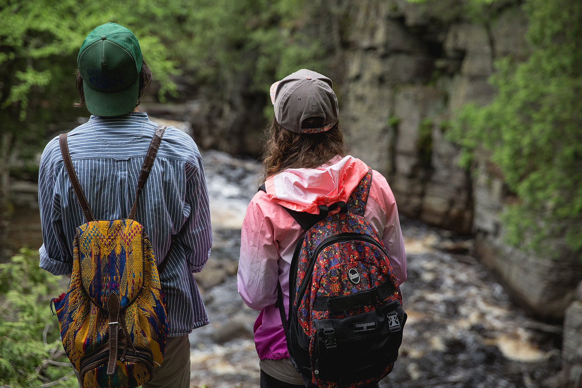 Two students wearing backpacks overlooking river