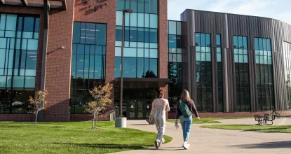 Two students walking to Jamrich Hall on sunny day