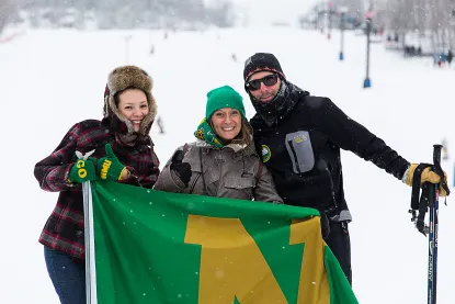 Skiers at Marquette Mountain holding an NMU flag