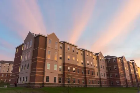 Exterior view of Cedar East, a four story stone and brick building.