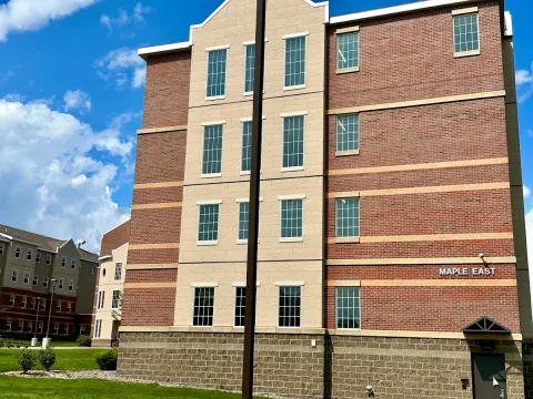 Exterior view of Maple East, a four story stone and brick building.