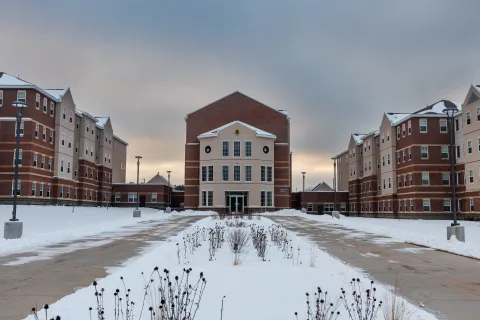 Maple West Residence Hall viewed from the front entrance, with snow-covered walkways and landscaped grounds.
