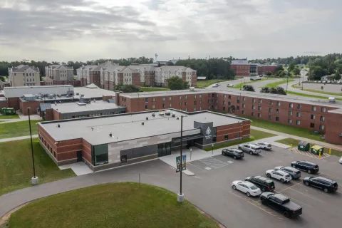 Aerial view of NMU’s WellBeing Center, with the parking lot in front and residence halls in the background.