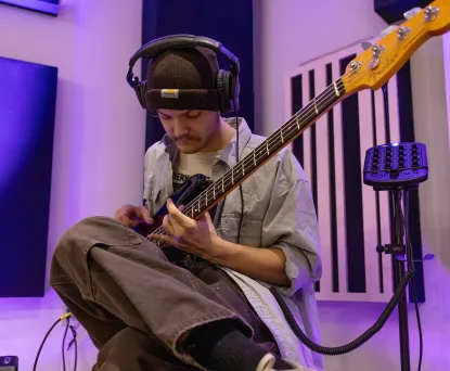 Student plays guitar in studio