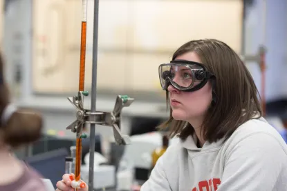 Student using a burette to titrate in a chemistry lab.