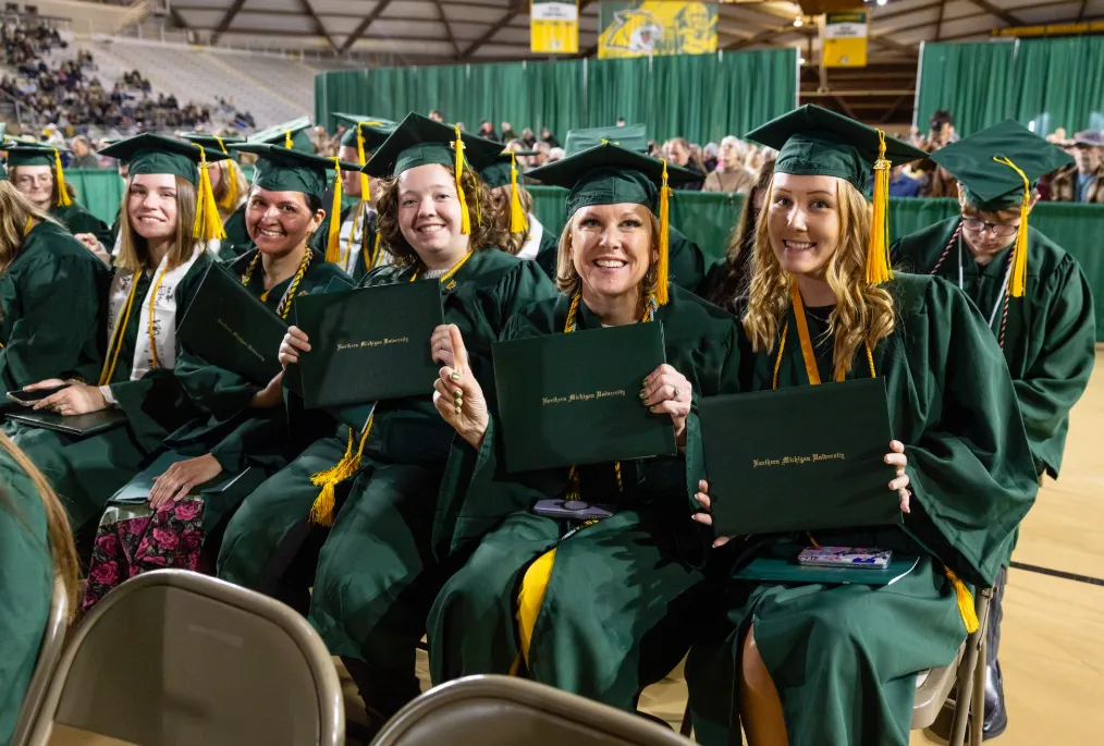 Students seated at commencement with their diploma covers