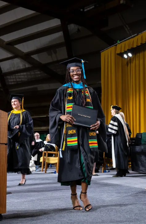Graduate student on stage with their diploma cover