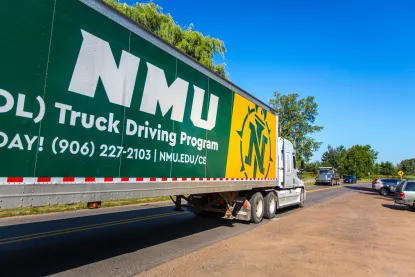 the side of a semi truck that has the words "NMU CDL Truck Driving Program" printed on it